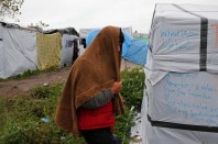 A migrant walks past tents and shelters in the makeshift camp called the "New Jungle" as unseasonably cool temperatures arrive in Calais, northern France, October 21, 2015. The number of migrants camped on France's north coast near Calais has doubled to around 6,000 in recent weeks, boosted by an influx across Europe's borders. Migrants and refugees are camped in Calais, fleeing war and poverty in the Middle East, Africa and Asia and now living in the jungle. Most of them are hoping to make the crossing to England.   REUTERS/Pascal Rossignol - RTS5GCR